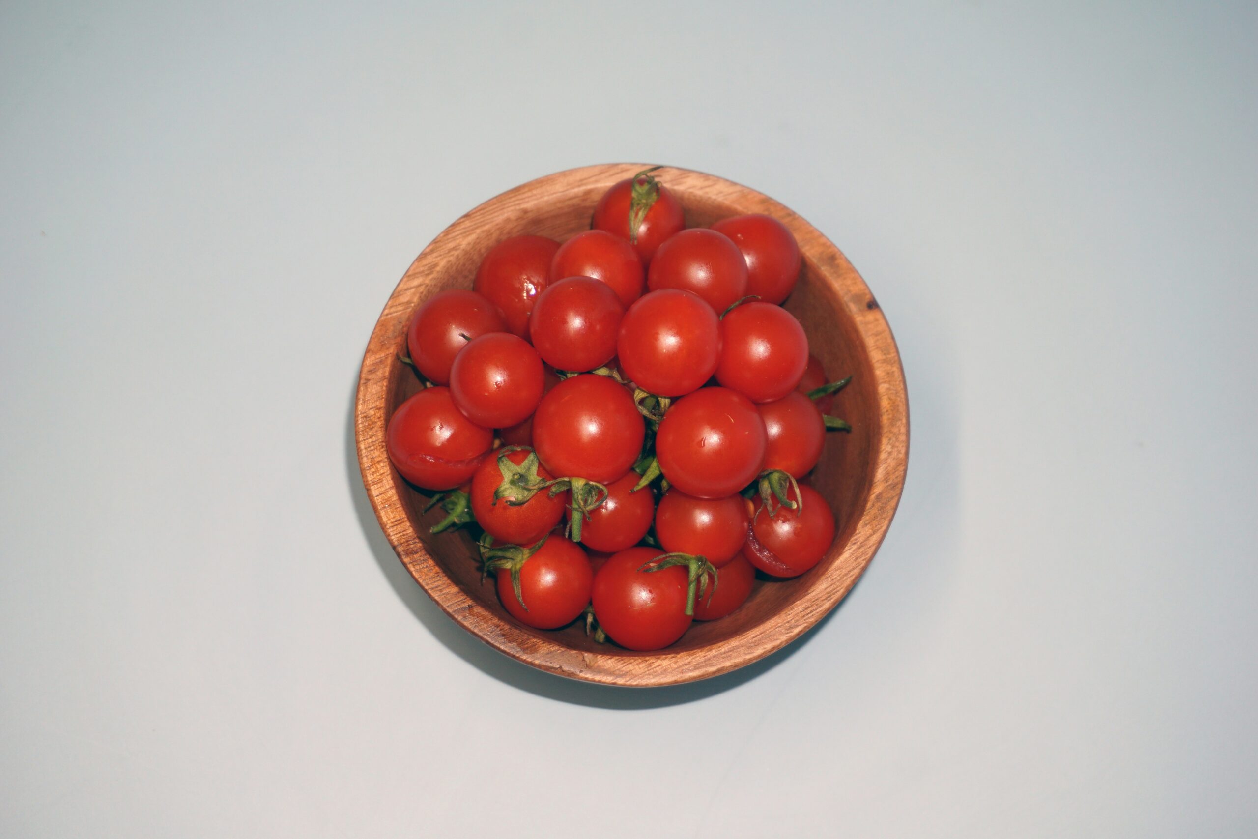 a wooden bowl filled with lots of red tomatoes